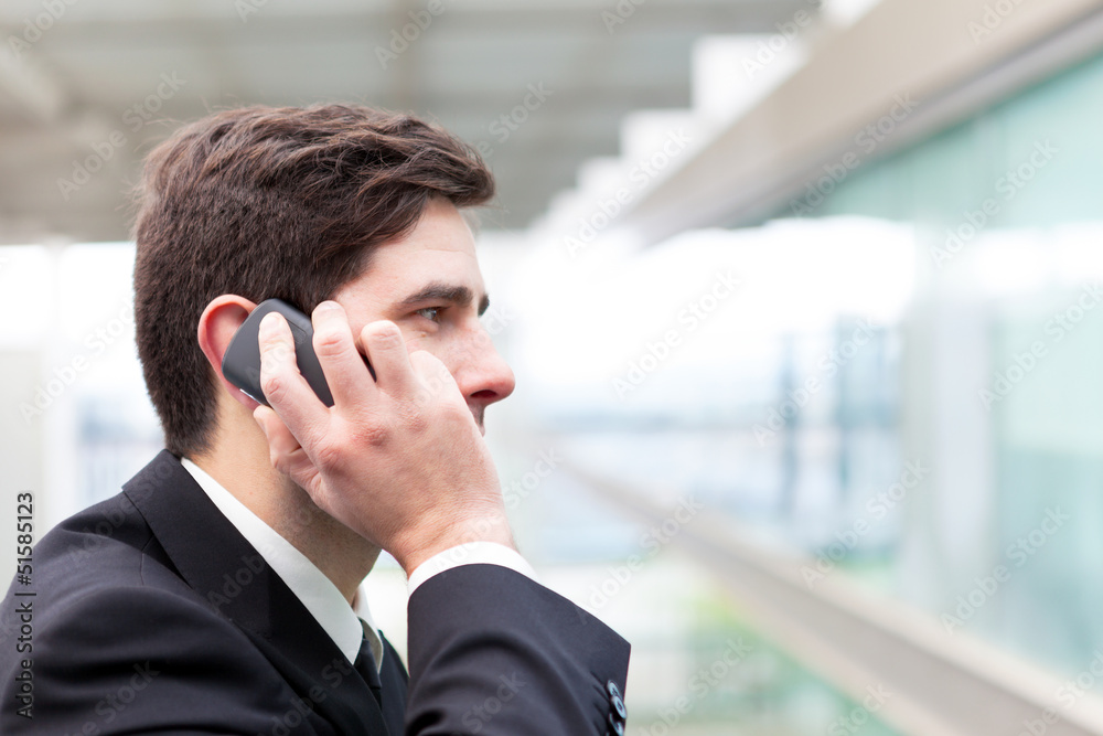 Closeup portrait of handsome business man using cell phone at th Closeup portrait of handsome business man using cell phone at th