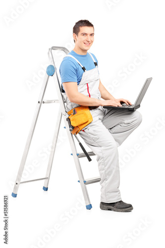 Full length portrait of a handy man with a laptop sitting on a l