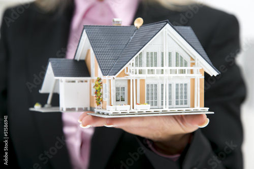 Foto Frau mit Luxus Haus auf der Hand im Anzug