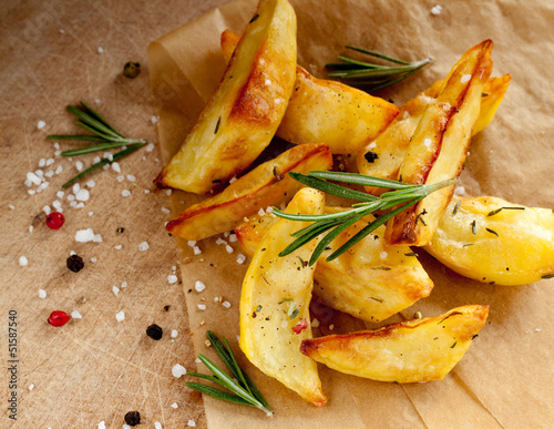 Rustic roasted potatoes with rosemary on wooden background