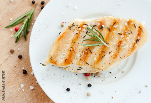 Grilled chicken breast with rosemary on white plate
