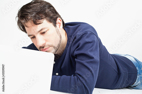 young man working on laptop while laying on the floor
