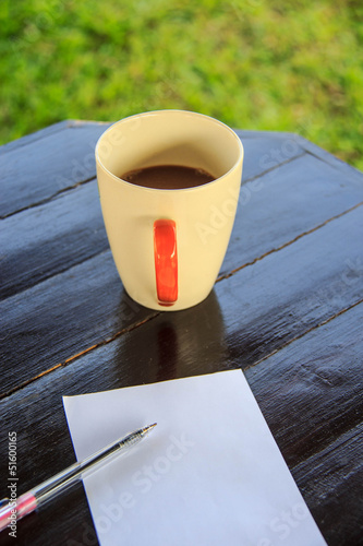 White paper note with pen with coffee cup on the table