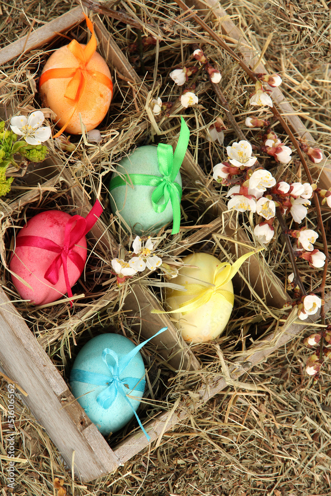Easter eggs in wooden box with hay close-up Easter eggs in wooden box with hay close-up
