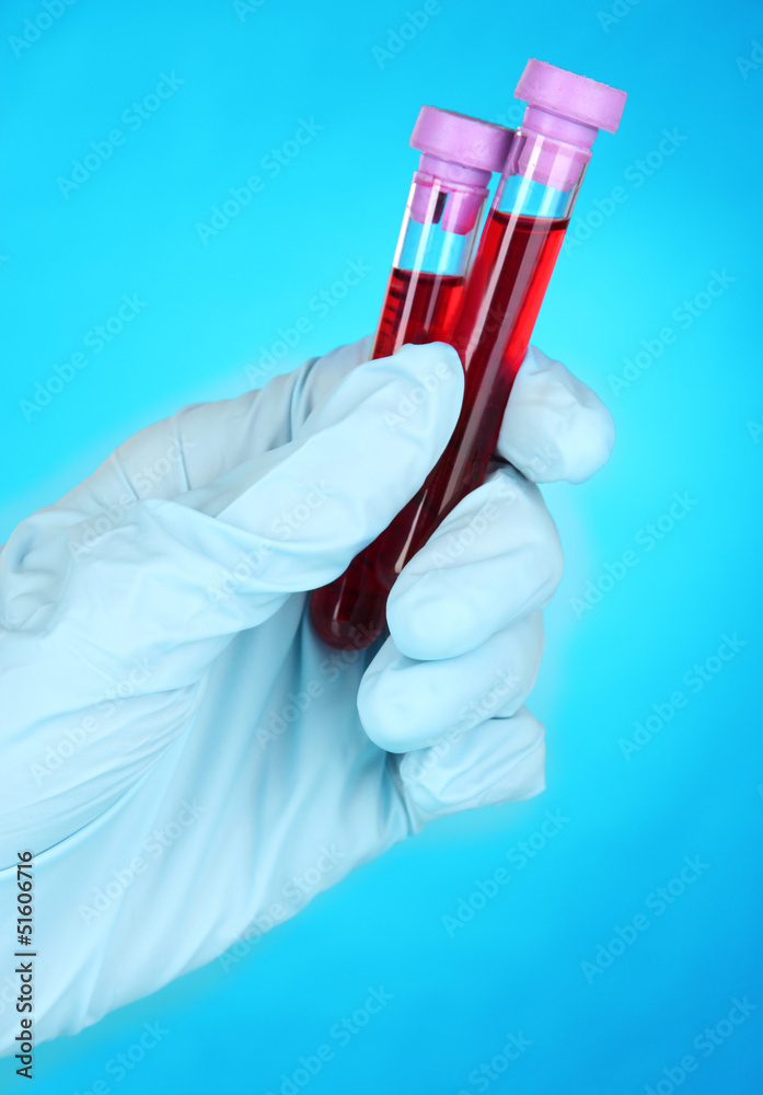 Test tubes with blood in hand on blue background Test tubes with blood in hand on blue background