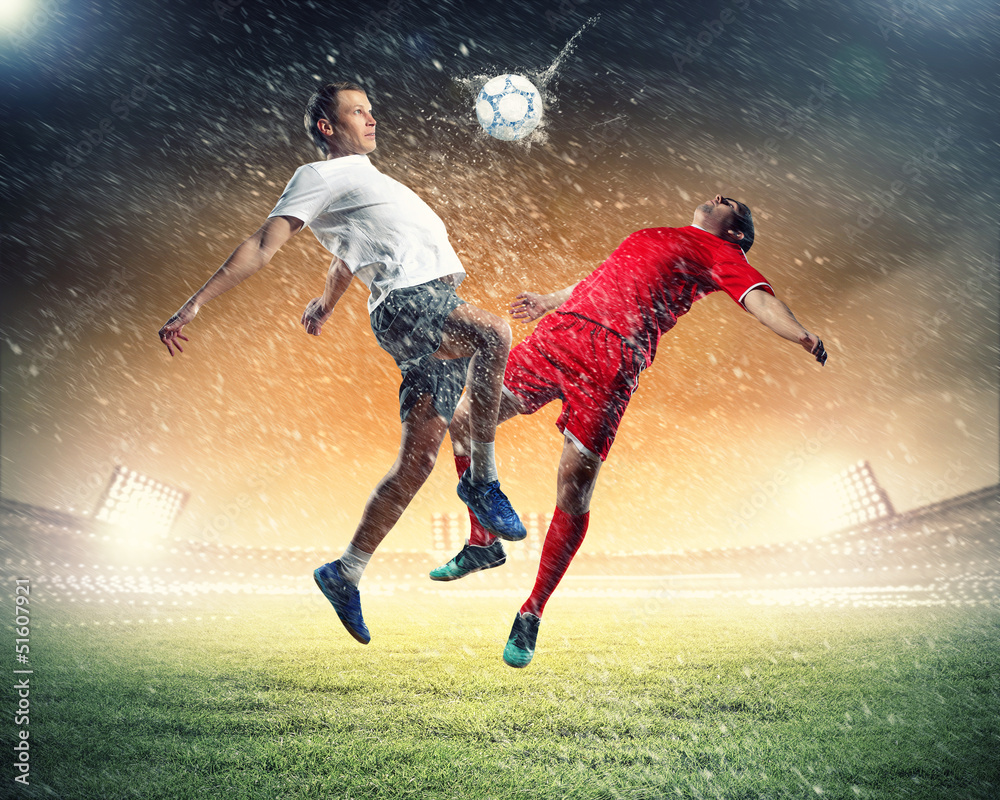 two football players striking the ball two football players striking the ball