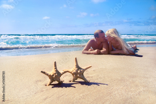loving couple lying on the sea sand beach against starfishs and