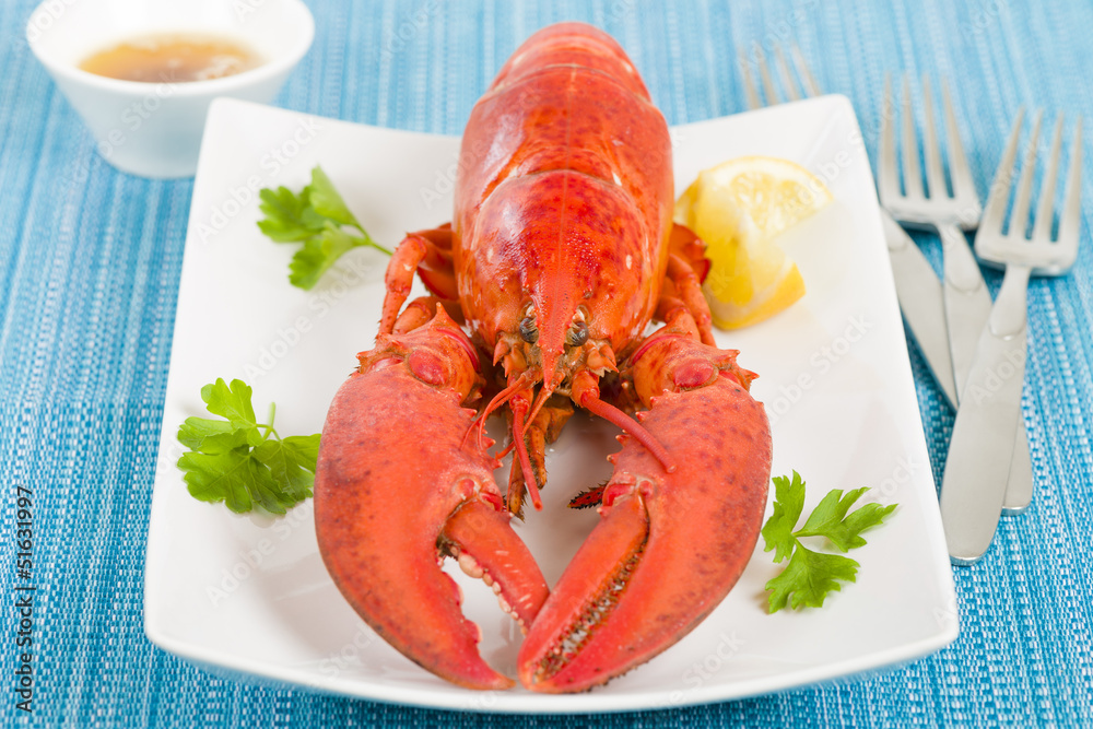 Lobster, browned butter and lemon wedges on a blue background Lobster, browned butter and lemon wedges on a blue background