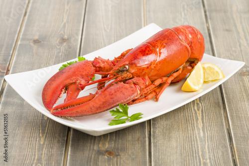 Lobster and lemon wedges on a wooden table.