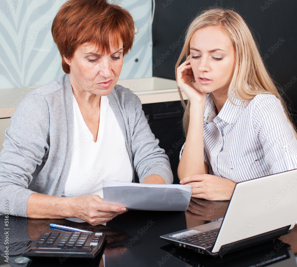 Two women discussing documents at home Two women discussing documents at home
