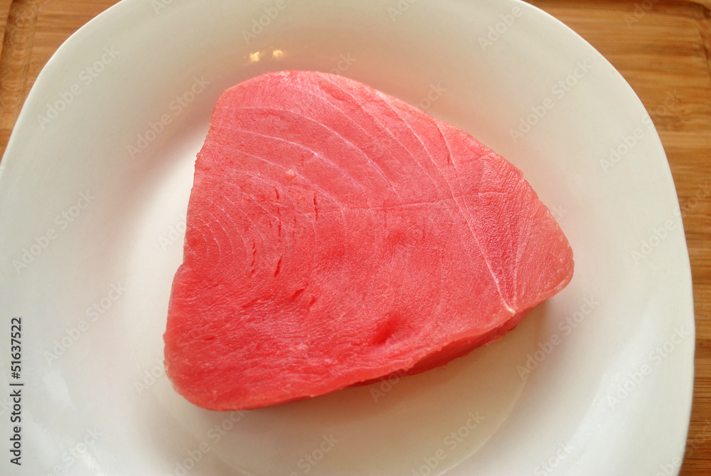 A Fresh Raw Tuna Steak on a White Plate A Fresh Raw Tuna Steak on a White Plate