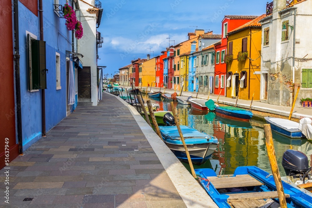 Burano street full of colorful houses and boats in the canal