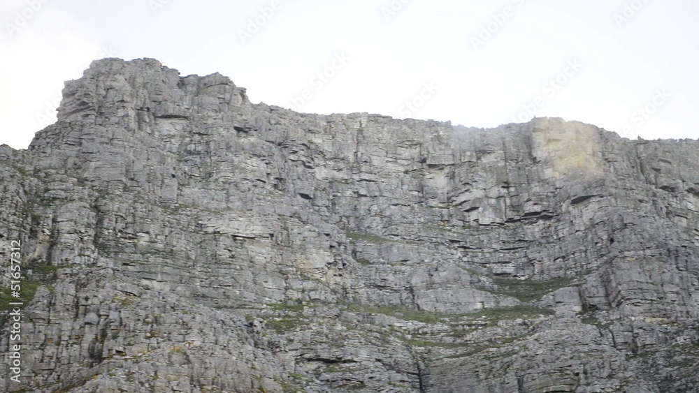 White clouds hanging above grey rocky part of Table Mountain
