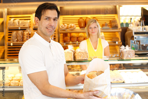 Happy customer in bakery with bags of bread