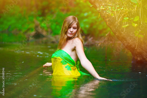 Fototapeta Naklejka Na Ścianę i Meble -  sunlight Blond young woman standing waist water in the river in