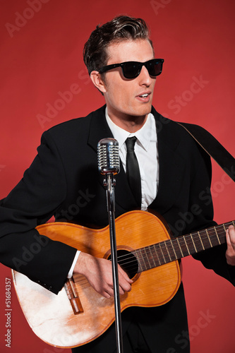 Retro fifties singer with sunglasses playing acoustic guitar. St