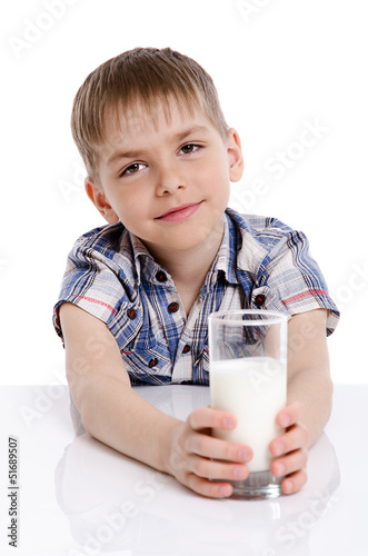 Happy kid with a glass of milk leaning on the table