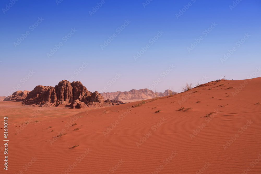 A red sand dune with a rock background in Wadi Rum desert