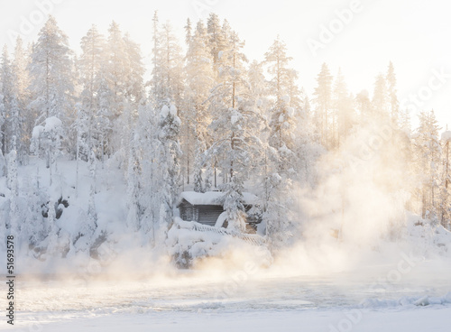 Small log cabin behind vaporing river photo