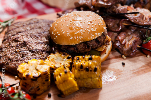 Set of grilled meat and burger on wooden board