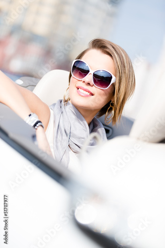 Close up of smiley woman in the car wearing cute sunglasses