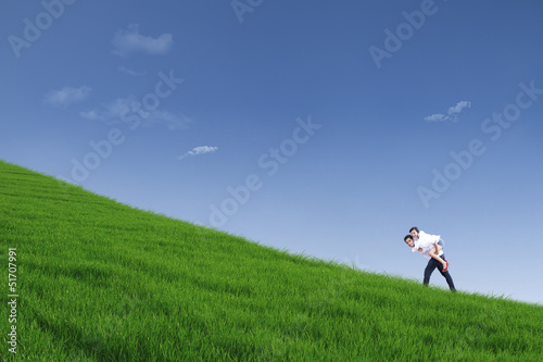 Guy giving piggyback ride on hill under blue sky