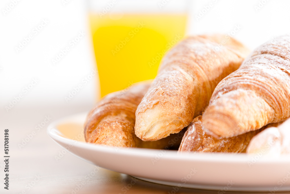 Close up of plate with croissants and a glass of citrus juice