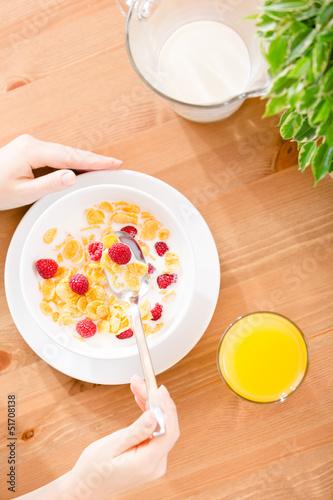 Top view of hands of the girl eating cereals with strawberry