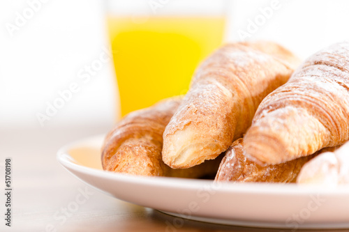 Close up of plate with croissants and a glass of citrus juice