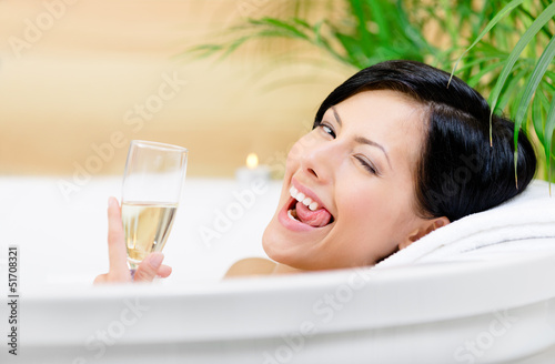 Woman taking a bath with suds drinks champagne