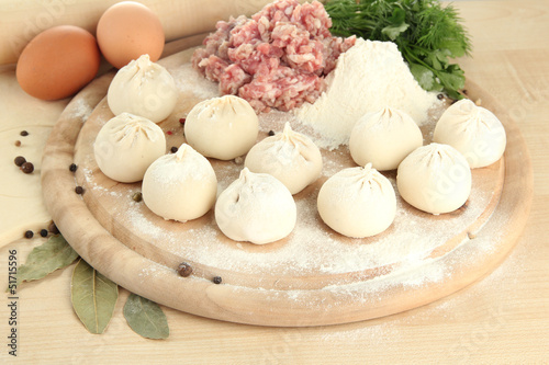 Raw dumplings and ingredients on wooden table