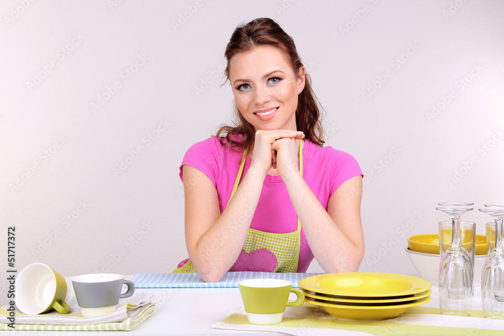 Beautiful young woman wipes clean utensils in kitchen Beautiful young woman wipes clean utensils in kitchen