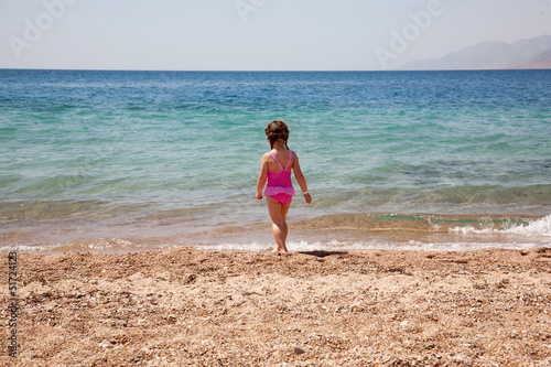 Little girl standing on beach in swimsuit. Rear view. © Vitalinka