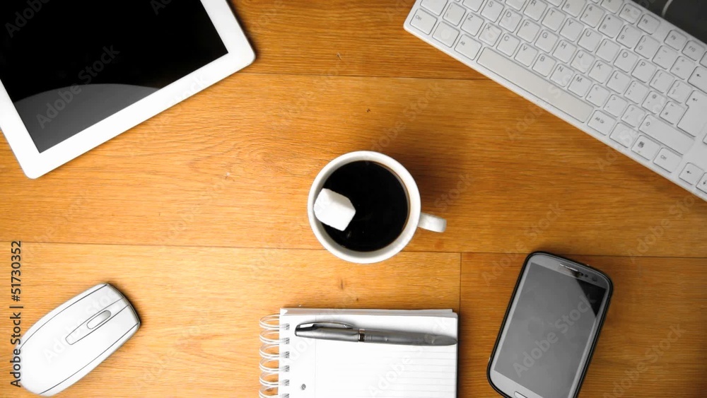 Sugar falling into coffee next to tablet pc and smartphone