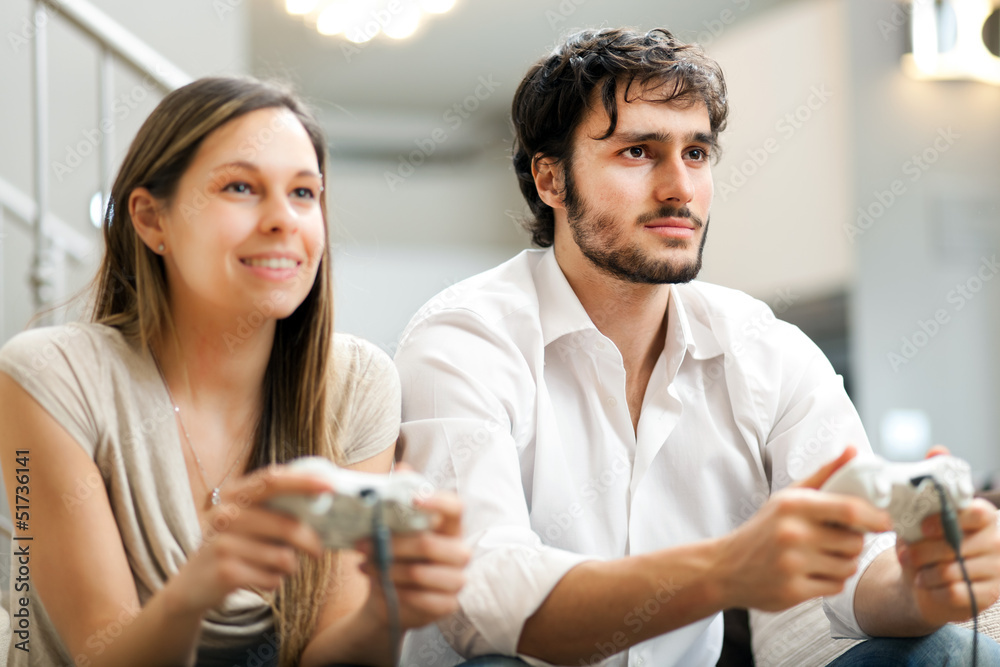 Couple playing video games on the sofa at home Couple playing video games on the sofa at home