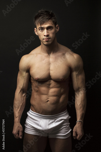 Muscular young man over black