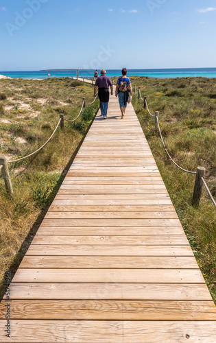 Tourists walking by beach way to Illetes beach in Formentera Bal