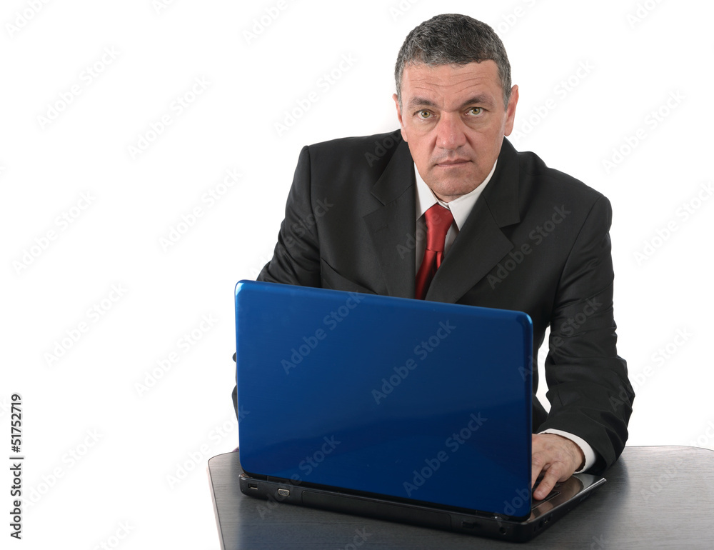Aged businessman sitting at desk with a laptop isolated on white Aged businessman sitting at desk with a laptop isolated on white
