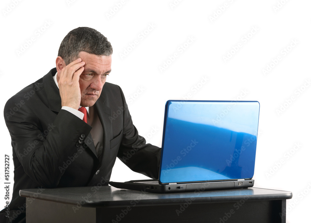 Aged businessman sitting at desk with a laptop isolated on white Aged businessman sitting at desk with a laptop isolated on white