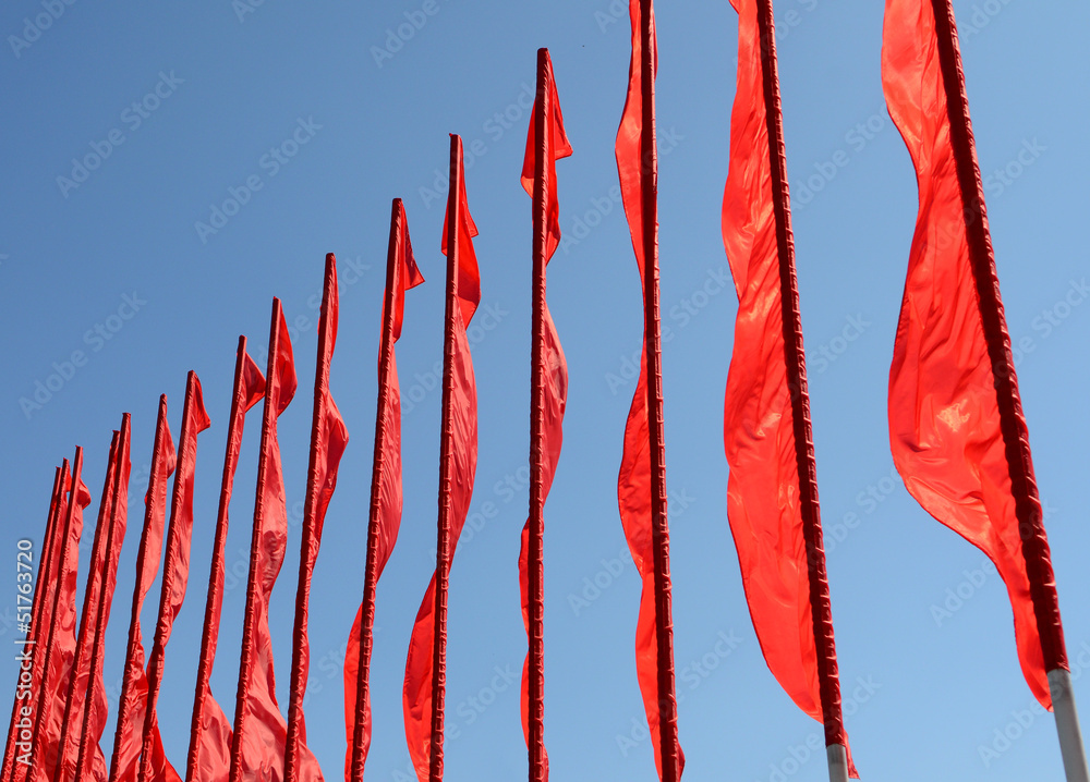 Красные флаги развеваются на ветру на фоне синего неба Stock Photo ...