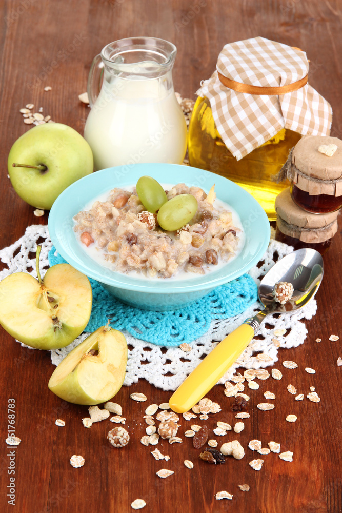Useful oatmeal in bowl with fruit on wooden table close-up