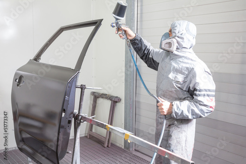 Car body painter spraying paint on bodywork parts