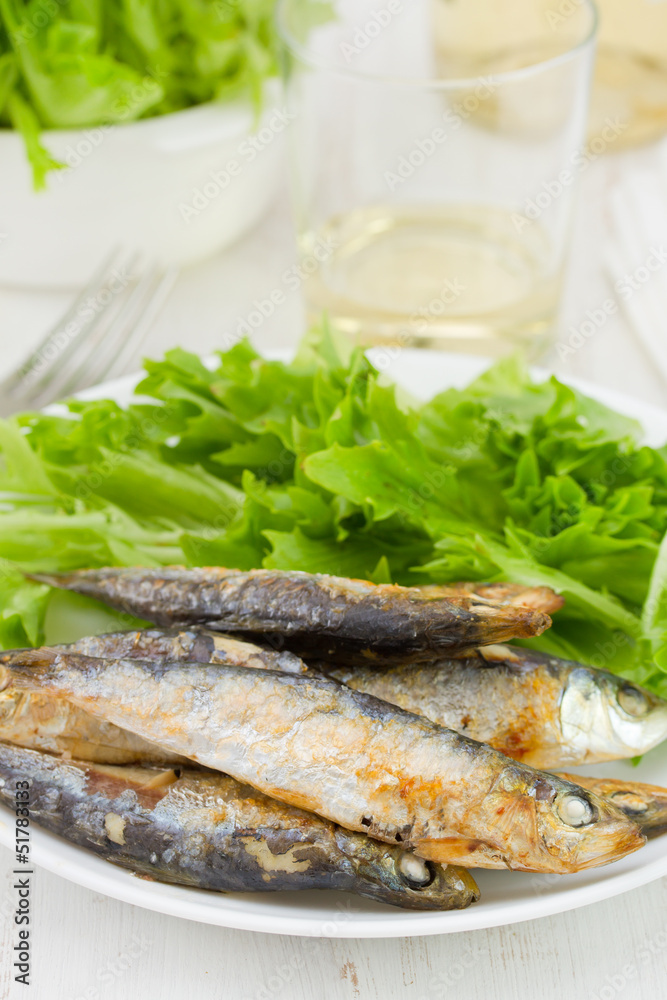 fried fish with salad and glass of wine