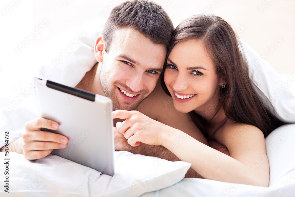 Couple in bed using digital tablet Couple in bed using digital tablet