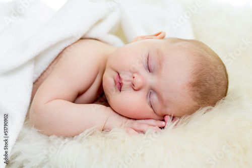 newborn baby girl sleeping on fur bed