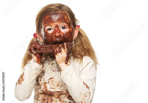 Little girl eating chocolate bar and face covered in chocolate photo