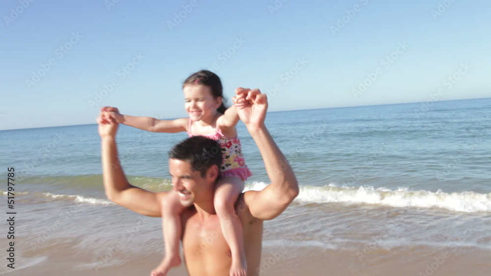 Father Carrying Daughter On Shoulders As They Run Out Of Sea Father Carrying Daughter On Shoulders As They Run Out Of Sea