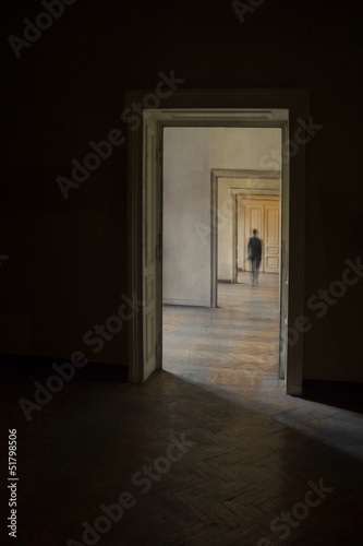 Silhouette in a corridor in front of a closed door.