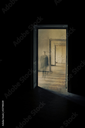 Silhouette in a corridor approaching  closed door behind