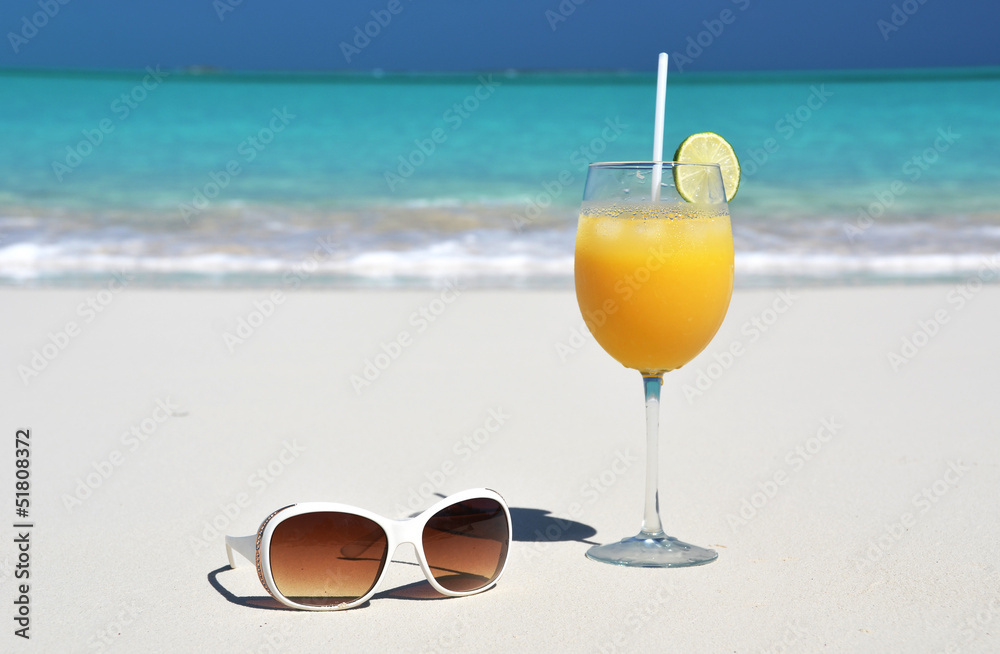 Orange juice and sunglasses on the beach. Exuma, Bahamas Orange juice and sunglasses on the beach. Exuma, Bahamas